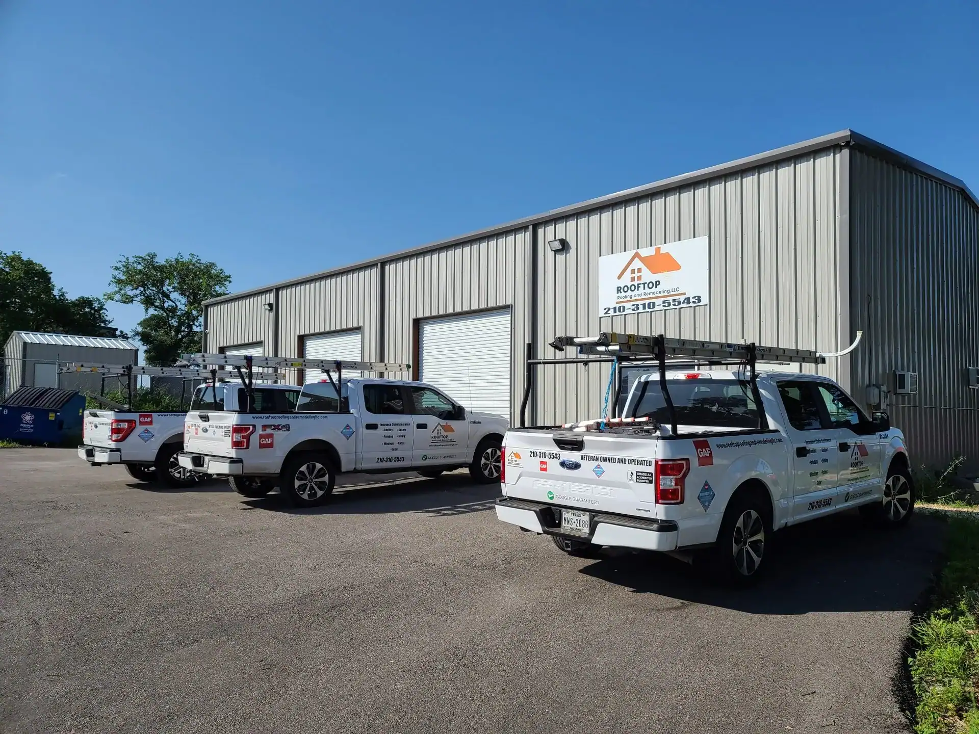 Rooftop Roofing and Remodeling company trucks parked outside a San Antonio commercial building